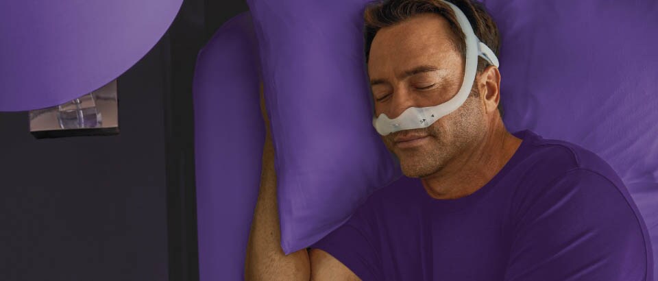 Hombre con camiseta morada que duerme con una mascarilla