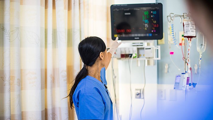 An acute care nurse turns off a bedside alarm